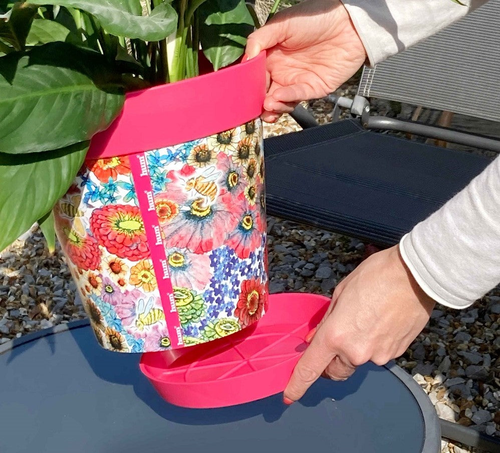 A pink flowers and bees patterned pot with matching pink saucer being picked up
