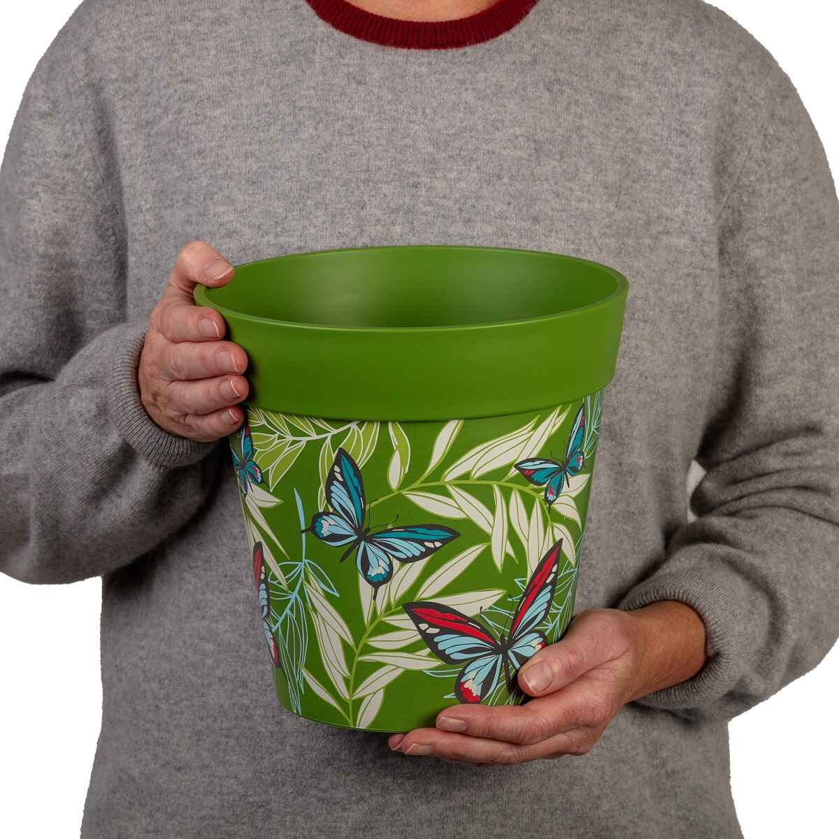 a person holding a 22xm green palm leaves and butterflies flowerpot