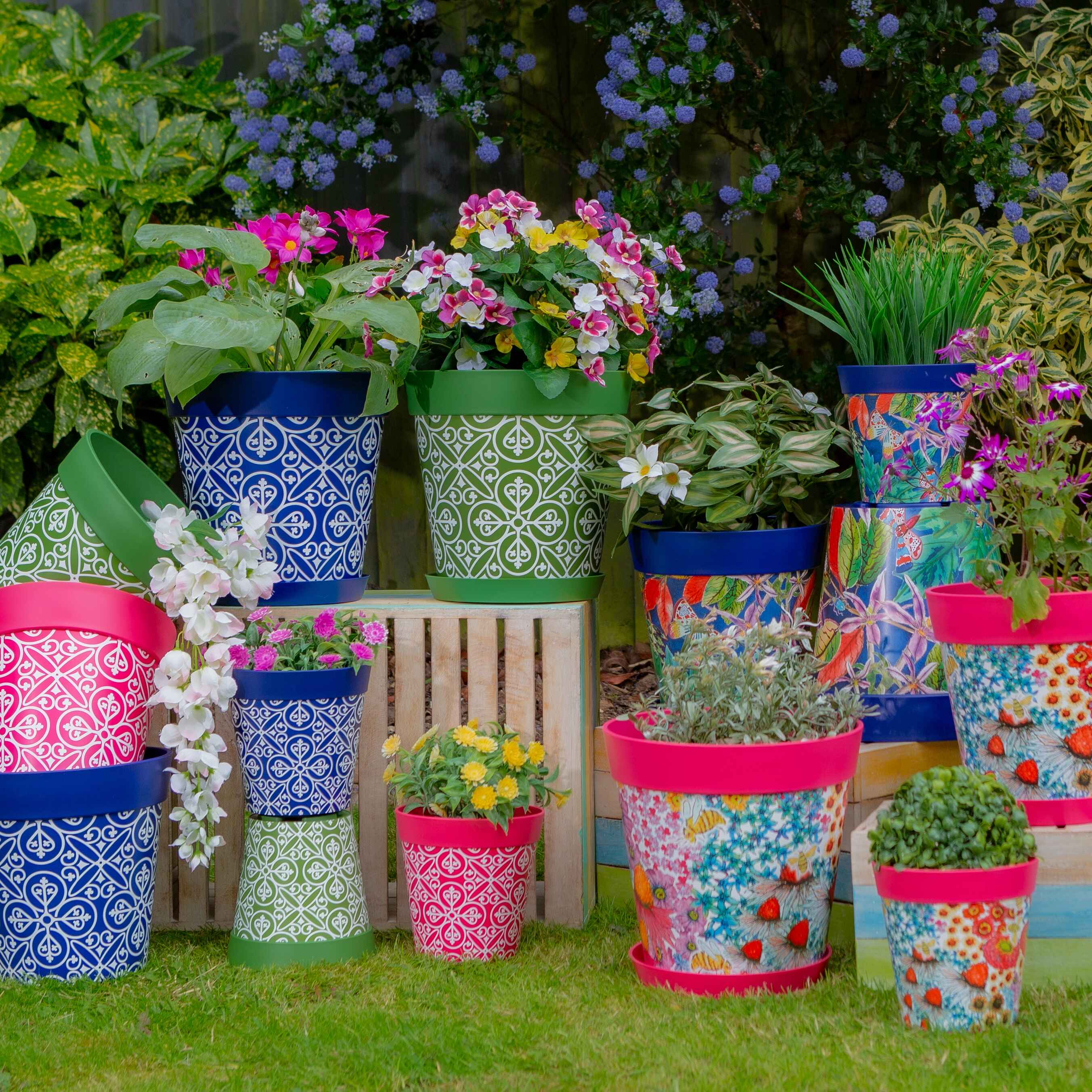 A variety of colourful flowerpots made of plastic, in a garden setting